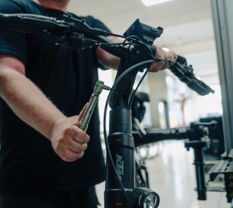 A man is standing and servicing a E-bike